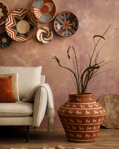 The stylish boho compostion at living room interior with design beige sofa, coffee table, wicker baskets and elegant personal accessories. Brown and white pillows and plaid. Cozy apartment Home decor