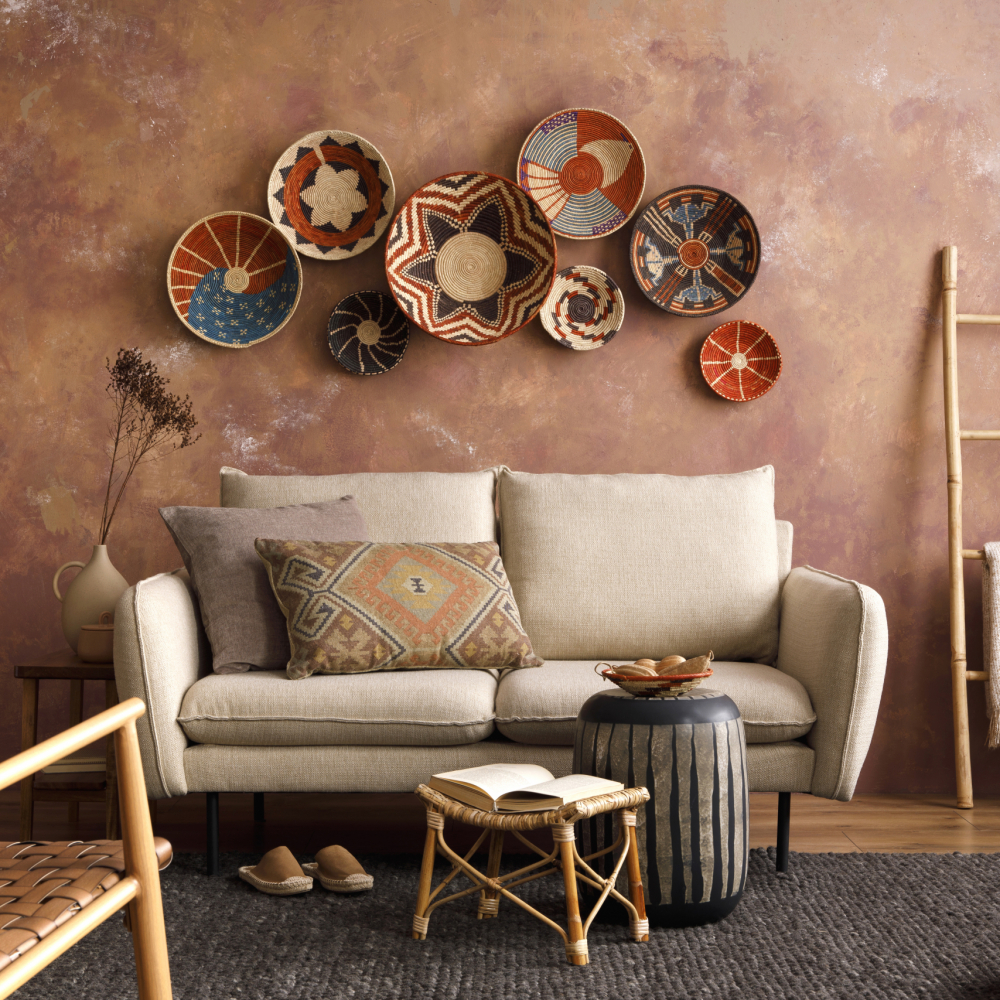 The stylish boho compostion at living room interior with design beige sofa, coffee table, wicker baskets and elegant personal accessories. Brown and white pillows and plaid. Cozy apartment. Home decor.